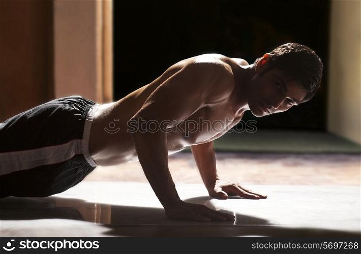 Portrait of young man doing push-ups in gym