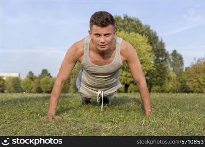 Portrait of young man doing pushups in park