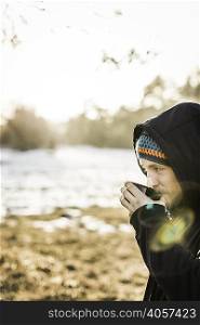 Portrait of young man drinking coffee at lakeside