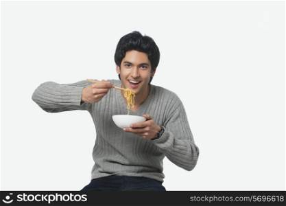 Portrait of young man eating noodles