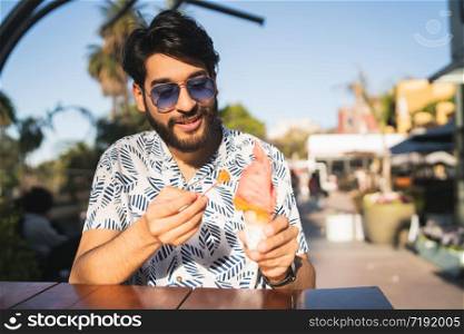 Portrait of young man enjoying sunny weather while eating an ice cream outdoors.