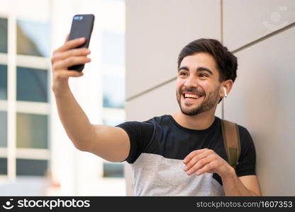 Portrait of young man having a video call on mobile phone while standing outdoors. Urban concept.. Young man having a video call on mobile phone.