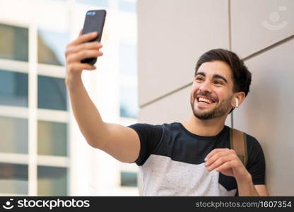 Portrait of young man having a video call on mobile phone while standing outdoors. Urban concept.. Young man having a video call on mobile phone.