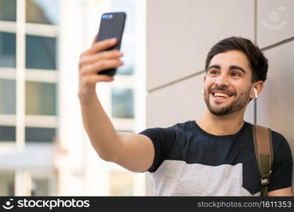 Portrait of young man having a video call on mobile phone while standing outdoors. Urban concept.. Young man having a video call on mobile phone.