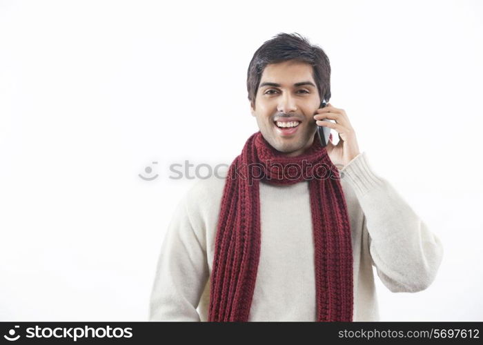 Portrait of young man having conversation on mobile phone over white background