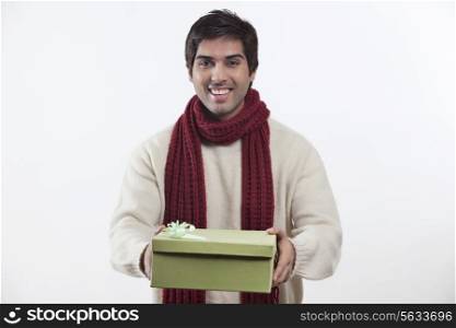 Portrait of young man holding gift box over white background