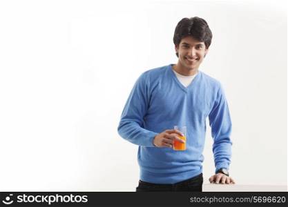 Portrait of young man holding glass of orange juice