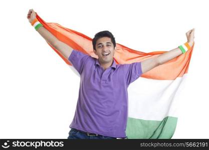Portrait of young man holding Indian flag with arms outstretched over white background