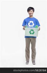 Portrait of young man holding recycling bin, studio shot