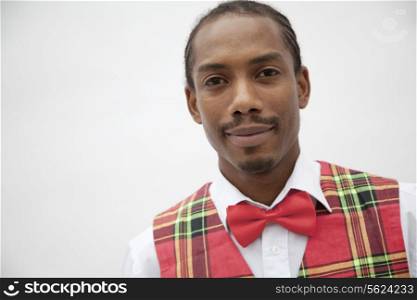 Portrait of young man in plaid vest and red bow tie, studio shot