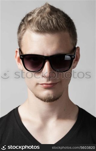 portrait of young man in sunglasses isolated on gray background