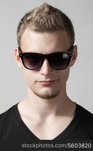 portrait of young man in sunglasses isolated on gray background