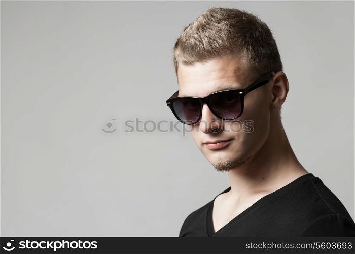 portrait of young man in sunglasses isolated on gray background with copyspace