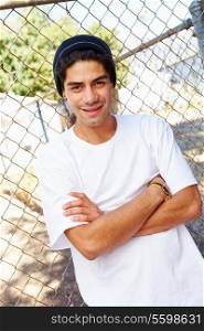 Portrait Of Young Man In Urban Setting Standing By Fence