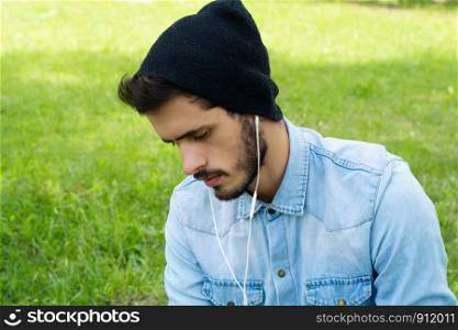 Portrait of young man listening to music with Earphones on a sunny day.