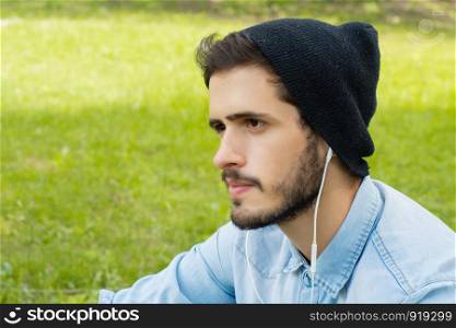 Portrait of young man listening to music with Earphones on a sunny day.