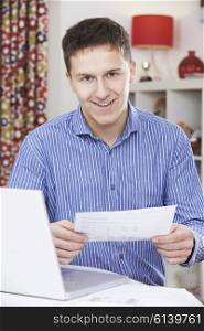 Portrait Of Young Man Looking At Domestic Bills