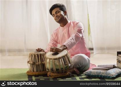 Portrait of young man playing Tabla at home
