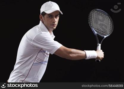 Portrait of young man playing tennis isolated over black background
