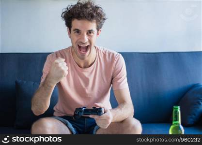 Portrait of young man playing video games in his living room. Technology and games concept.