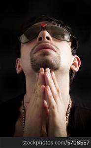 Portrait of young man praying in sunglasses