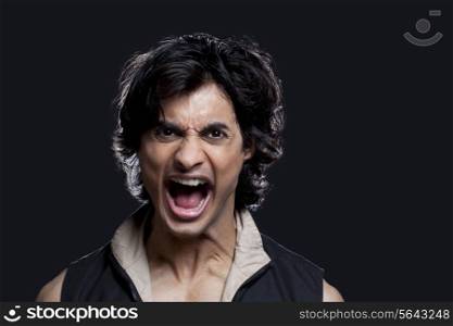 Portrait of young man screaming against black background