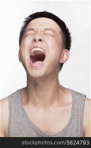 Portrait of young man screaming, mouth open, studio shot