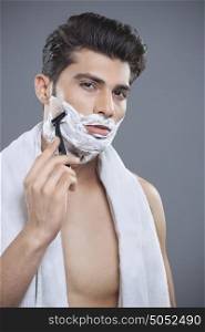 Portrait of young man shaving