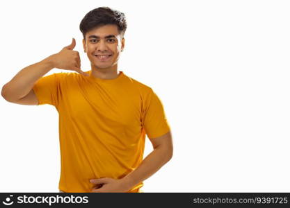 Portrait of young man showing calling gesture against white background