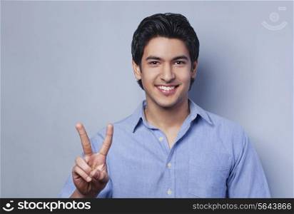 Portrait of young man showing V-sign