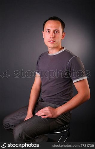 portrait of young man sits on stool