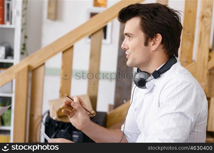 Portrait of young man sitting at the stairs in office. Portrait of young businessman sitting at the stairs in office with headphones