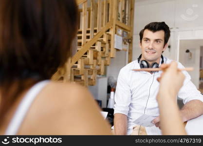 Portrait of young man sitting at the stairs in office. Portrait of young businessman sitting at the stairs in office with headphones