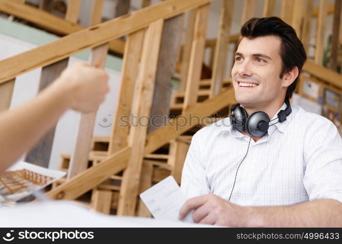 Portrait of young man sitting at the stairs in office. Portrait of young businessman sitting at the stairs in office with headphones