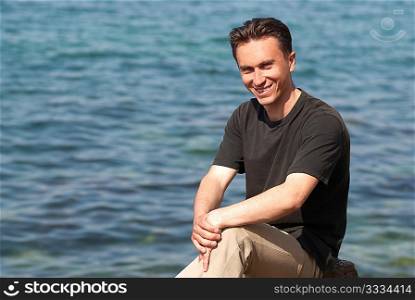Portrait of young man sitting near the blue sea
