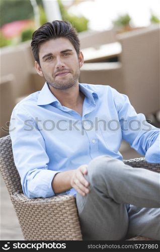 Portrait of young man sitting on chair at outdoors cafe