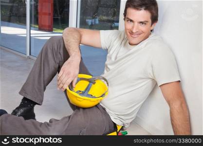Portrait of young man sitting with construction helmet