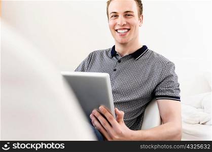 Portrait of young man sitting with digital tablet