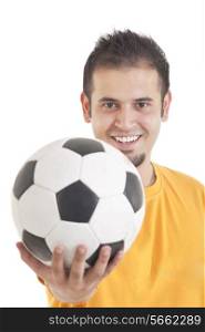 Portrait of young man smiling while holding soccer ball over white background