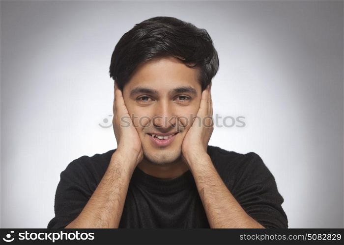 Portrait of Young man smiling with hands on cheek