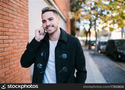 Portrait of young man talking on the phone outdoors in the street. Communication and urban concept.