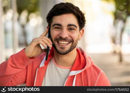 Portrait of young man talking on the phone while standing outdoors on the street. Urban concept.