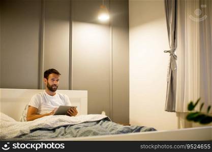 Portrait of young man using digital tablet lying on bed