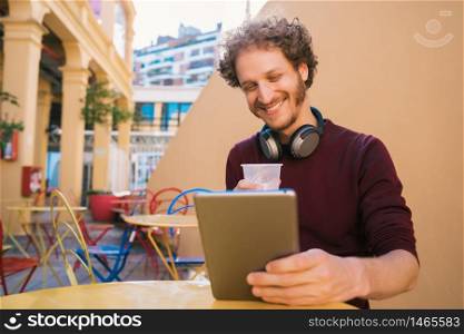 Portrait of young man using his digital tablet while drinking beer. Technology and lifestyle concept