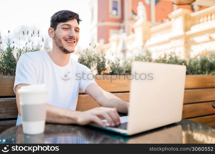 Portrait of young man using his laptop while sitting in a coffee shop. Technology and lifestyle concept.