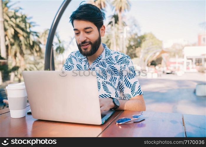 Portrait of young man using his laptop while sitting in a coffee shop. Technology and business concept.