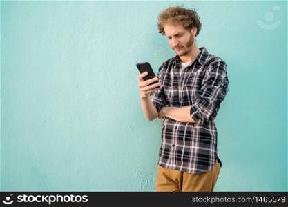 Portrait of young man using his mobile phone against blue background. Communication concept.