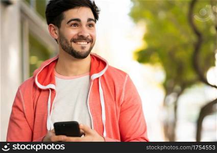 Portrait of young man using his mobile phone while walking outdoors on the street. Urban concept.