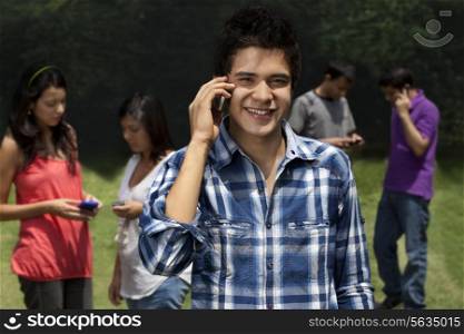 Portrait of young man using phone with friends in the background