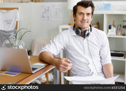 Portrait of young man wearing casual in office. Portrait of young businessman in office with headphones